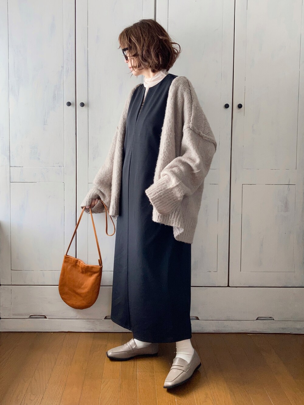 ブラック系のワンピース、ベージュ系のカーディガン/ボレロ、ホワイト系のローファーを着用したレディースの冬コーディネートの2枚目の写真