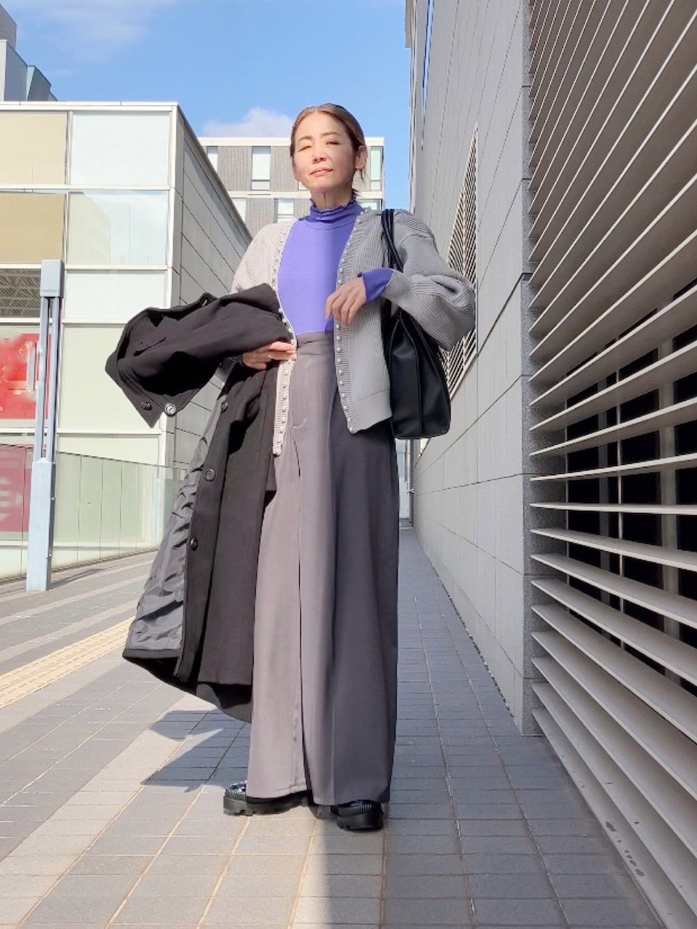 グレー系のカーディガン/ボレロ、ブラック系のステンカラーコート、グレー系のその他パンツを着用したレディースの冬コーディネートの2枚目の写真