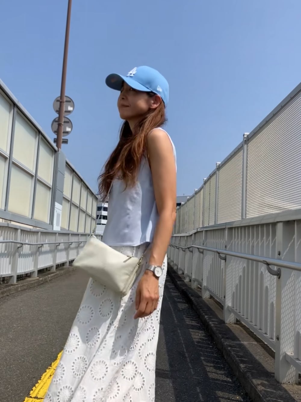ホワイト系のショルダーバッグ、ブルー系のキャップを着用したレディースの夏コーディネートの3枚目の写真