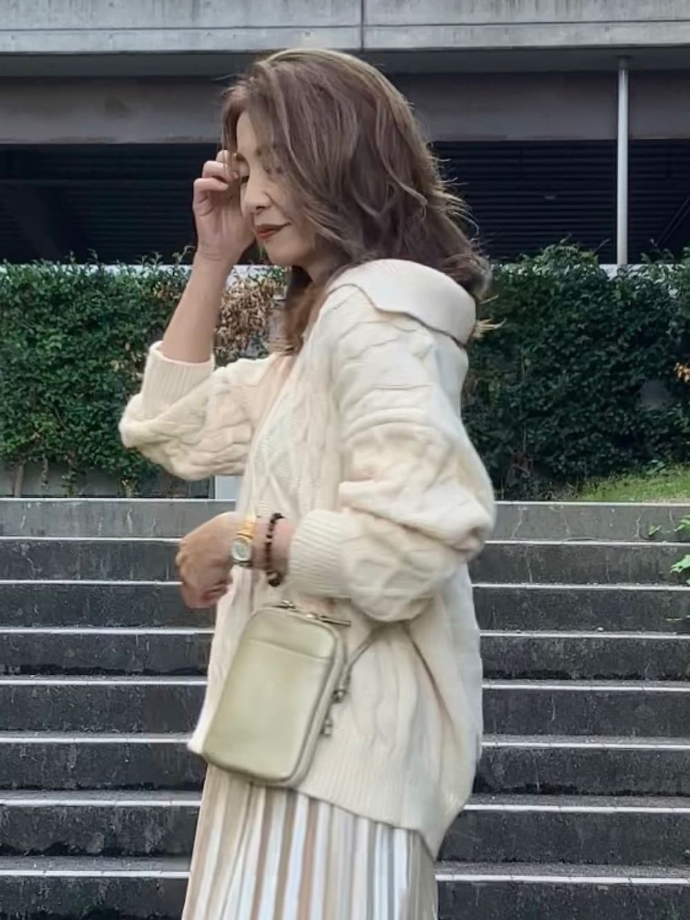 ホワイト系のニット/セーター、ベージュ系のスカート、ゴールド系のバッグを着用したレディースの秋コーディネートの2枚目の写真