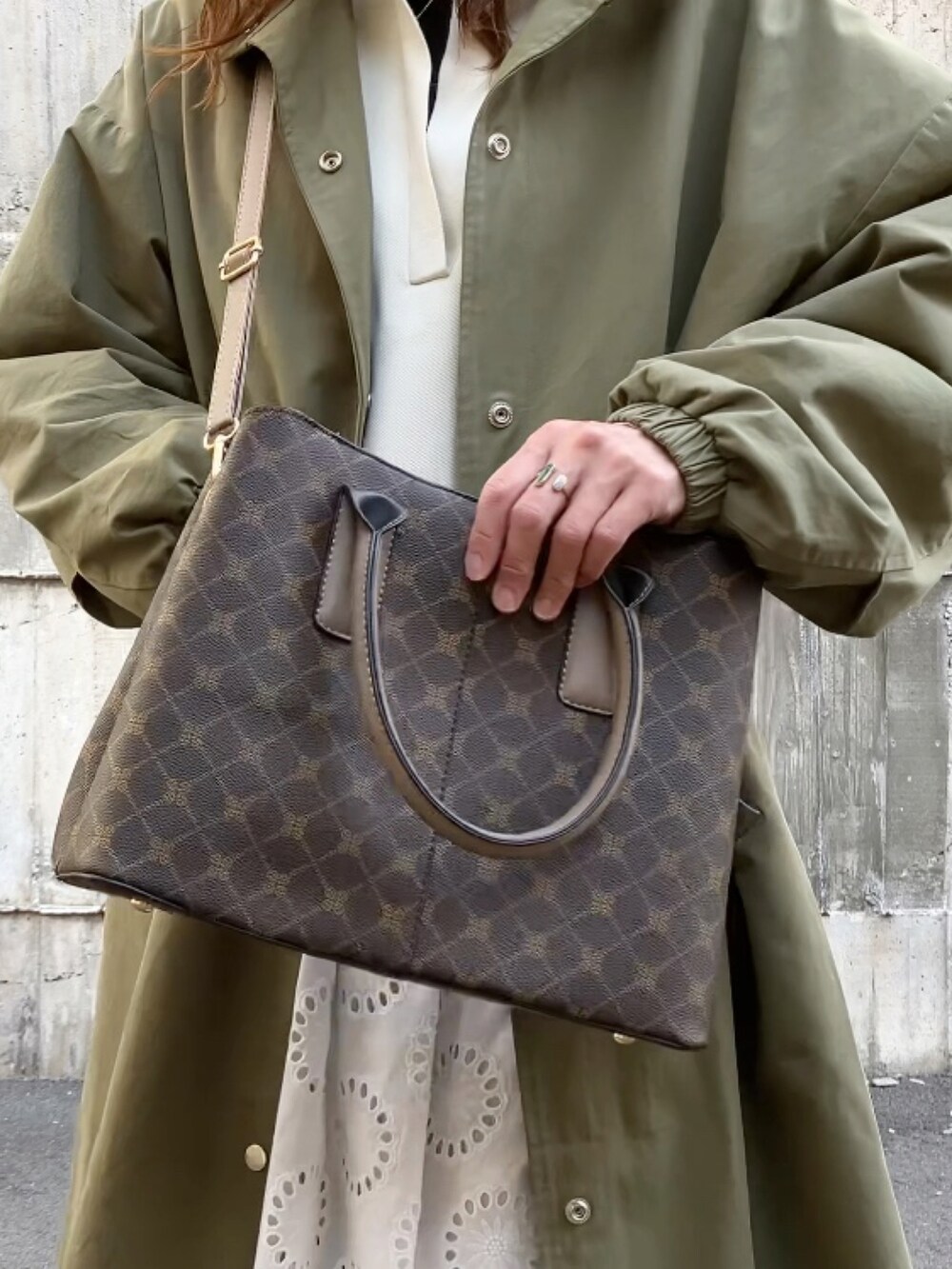 グリーン系のステンカラーコート、ブラウン系のハンドバッグ、ホワイト系のワンピース/ドレスを着用したレディースの冬コーディネートの2枚目の写真