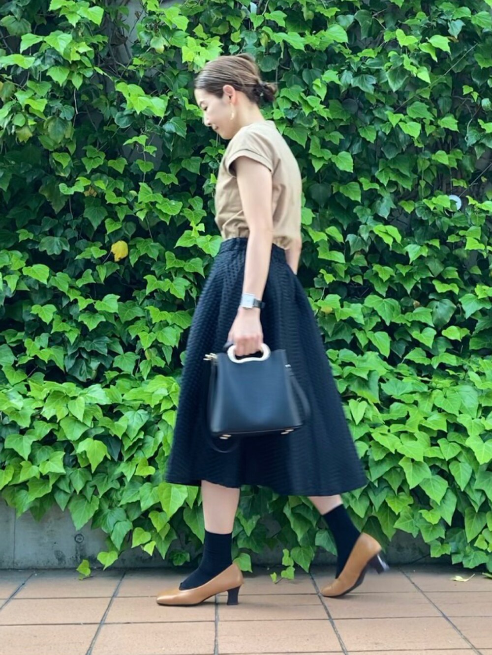 ベージュ系のTシャツ/カットソー、ブラック系のスカート、ベージュ系のパンプスを着用したレディースの夏コーディネートの3枚目の写真