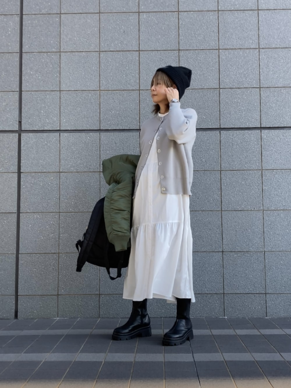 グリーン系のMA-1、グレー系のカーディガン/ボレロ、ブラック系のブーツを着用したレディースの冬コーディネートの2枚目の写真