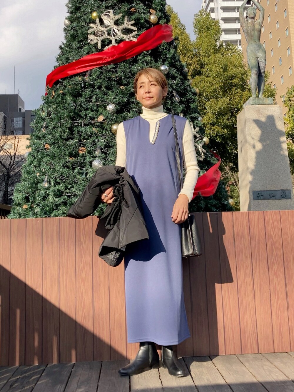 ブラック系のダウンジャケット/コート、ブルー系のワンピース、ブラック系のハンドバッグを着用したレディースの冬コーディネートの2枚目の写真