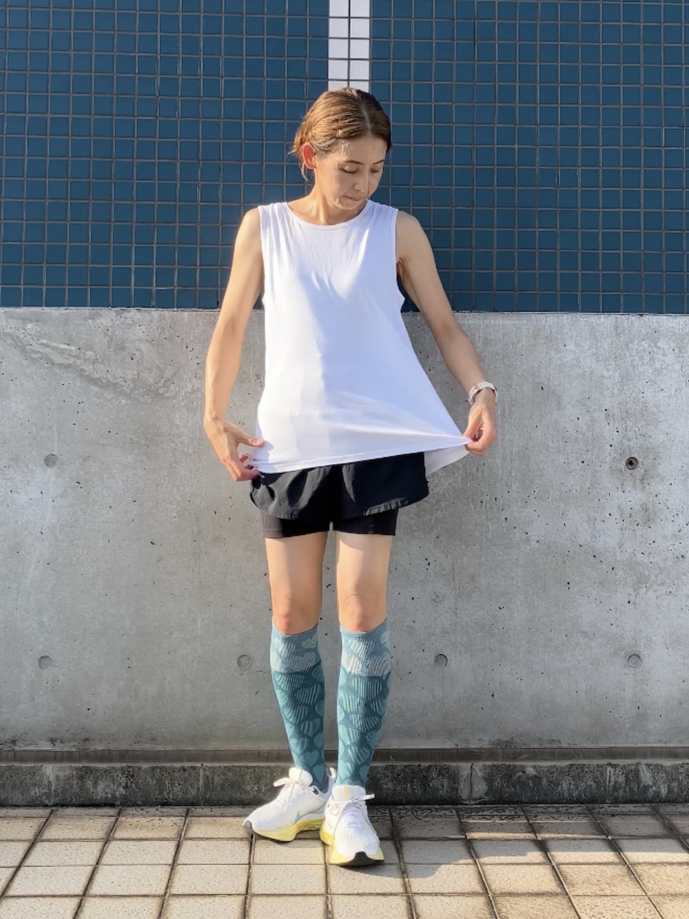 ホワイト系のタンクトップ、ブルー系のデニムパンツ、ブラック系のショルダーバッグを着用したレディースの夏コーディネートの4枚目の写真