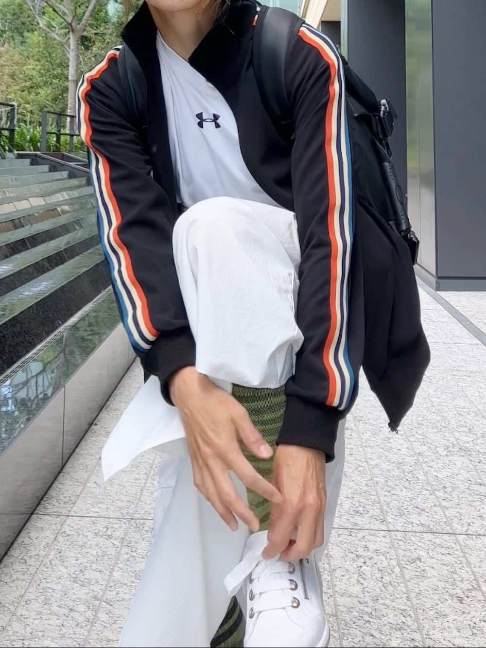 ブラック系のジャージ、ブラック系のバックパック/リュック、ホワイト系のスニーカーを着用したレディースの秋コーディネートの4枚目の写真