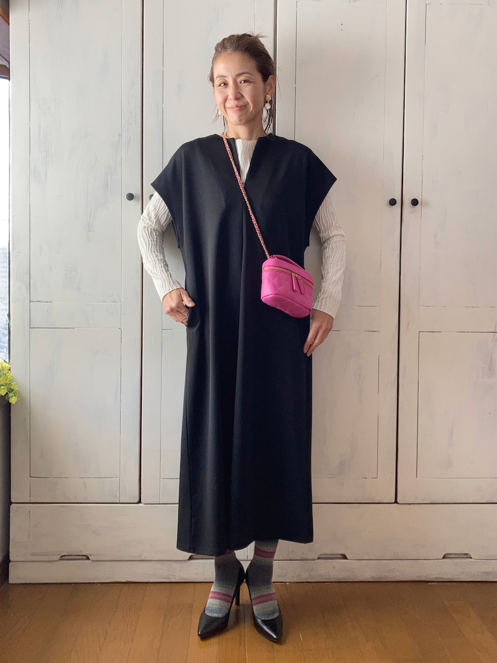 ブラック系のワンピース、ホワイト系のTシャツ/カットソー、ピンク系のショルダーバッグを着用したレディースの冬コーディネートの2枚目の写真