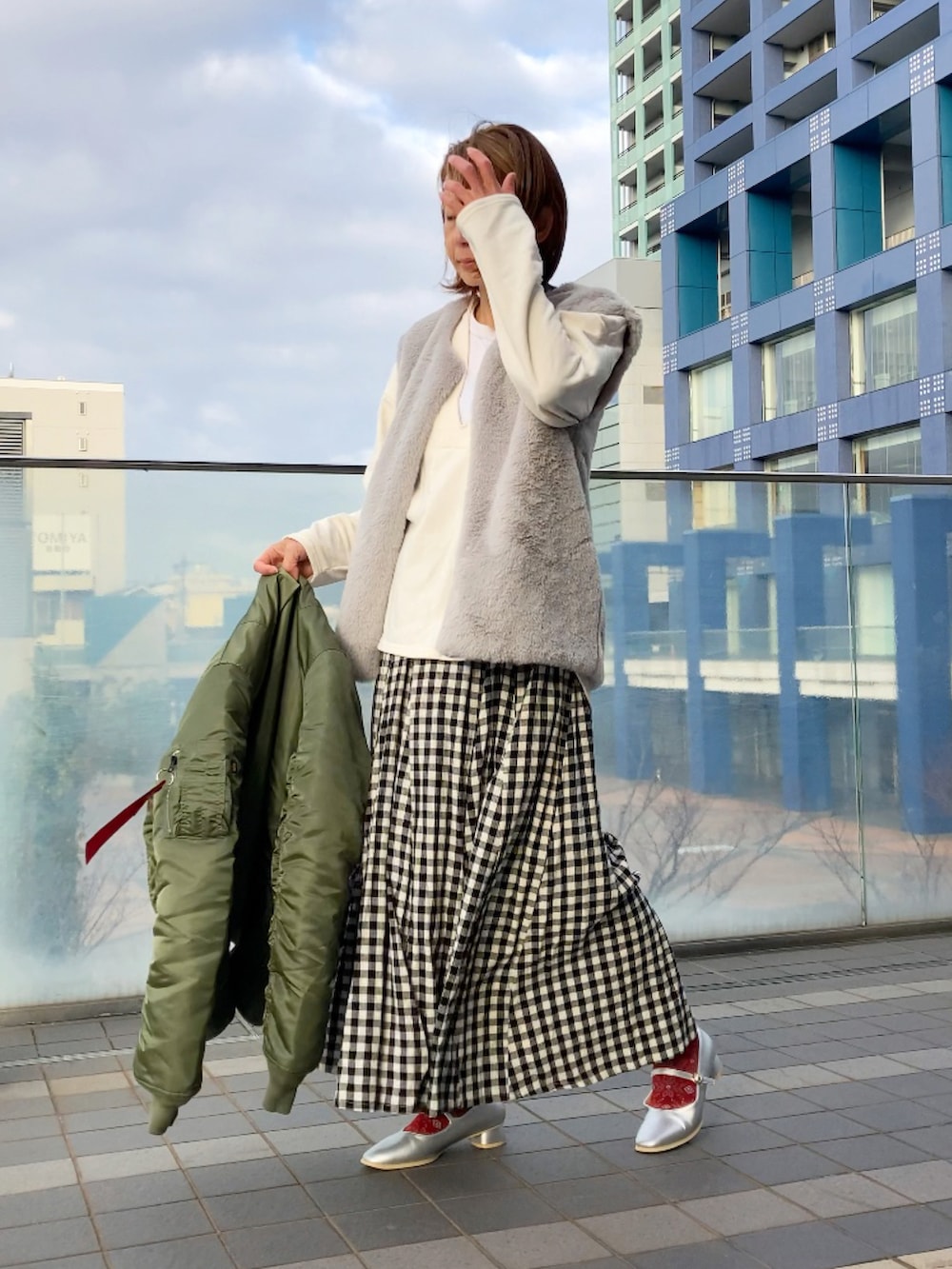 グリーン系のMA-1、ホワイト系のスウェット、グレー系のベストを着用したレディースの冬コーディネートの2枚目の写真