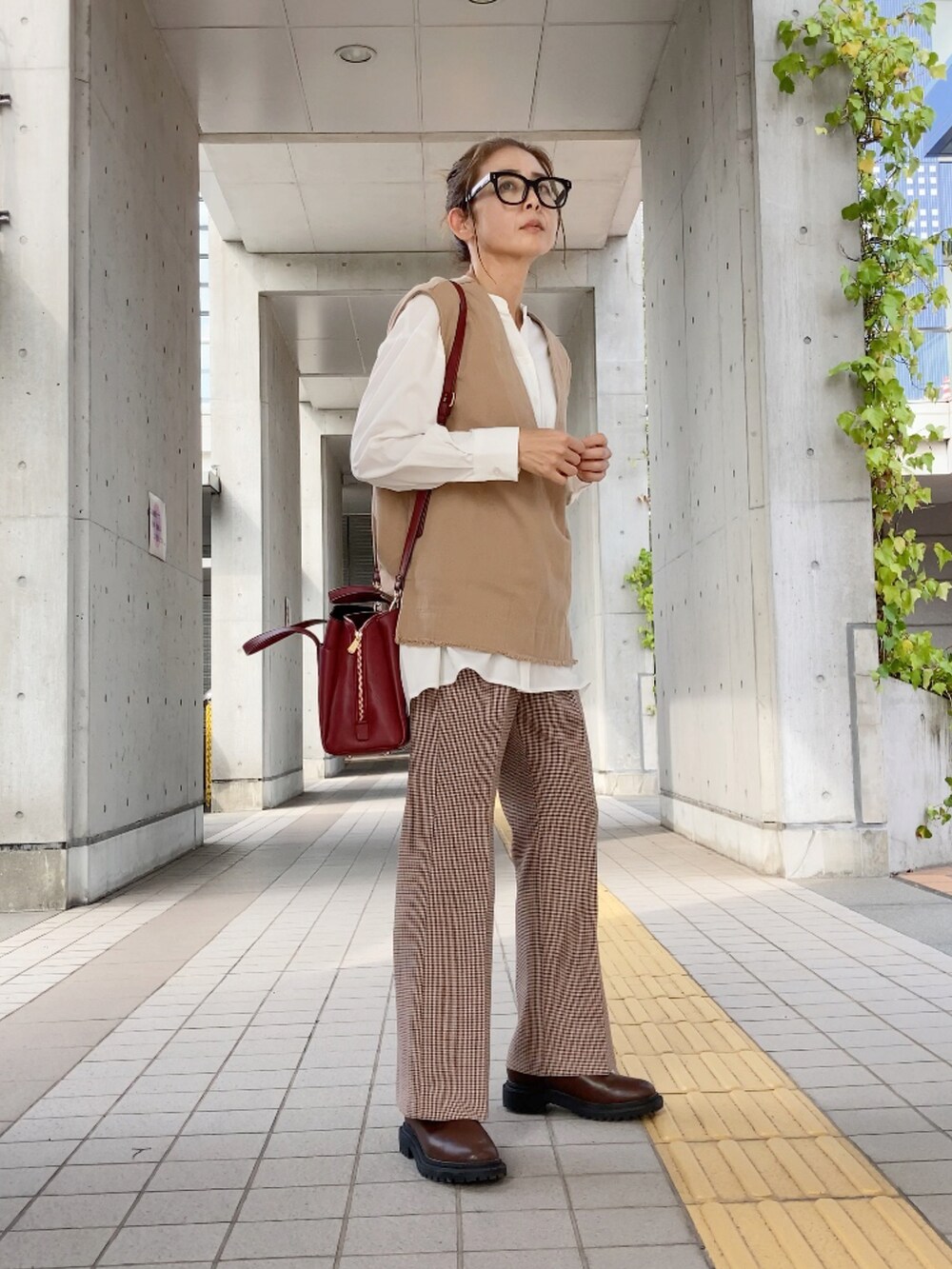 ベージュ系のベスト、ホワイト系のシャツ/ブラウス、レッド系のハンドバッグを着用したレディースの秋コーディネートの2枚目の写真