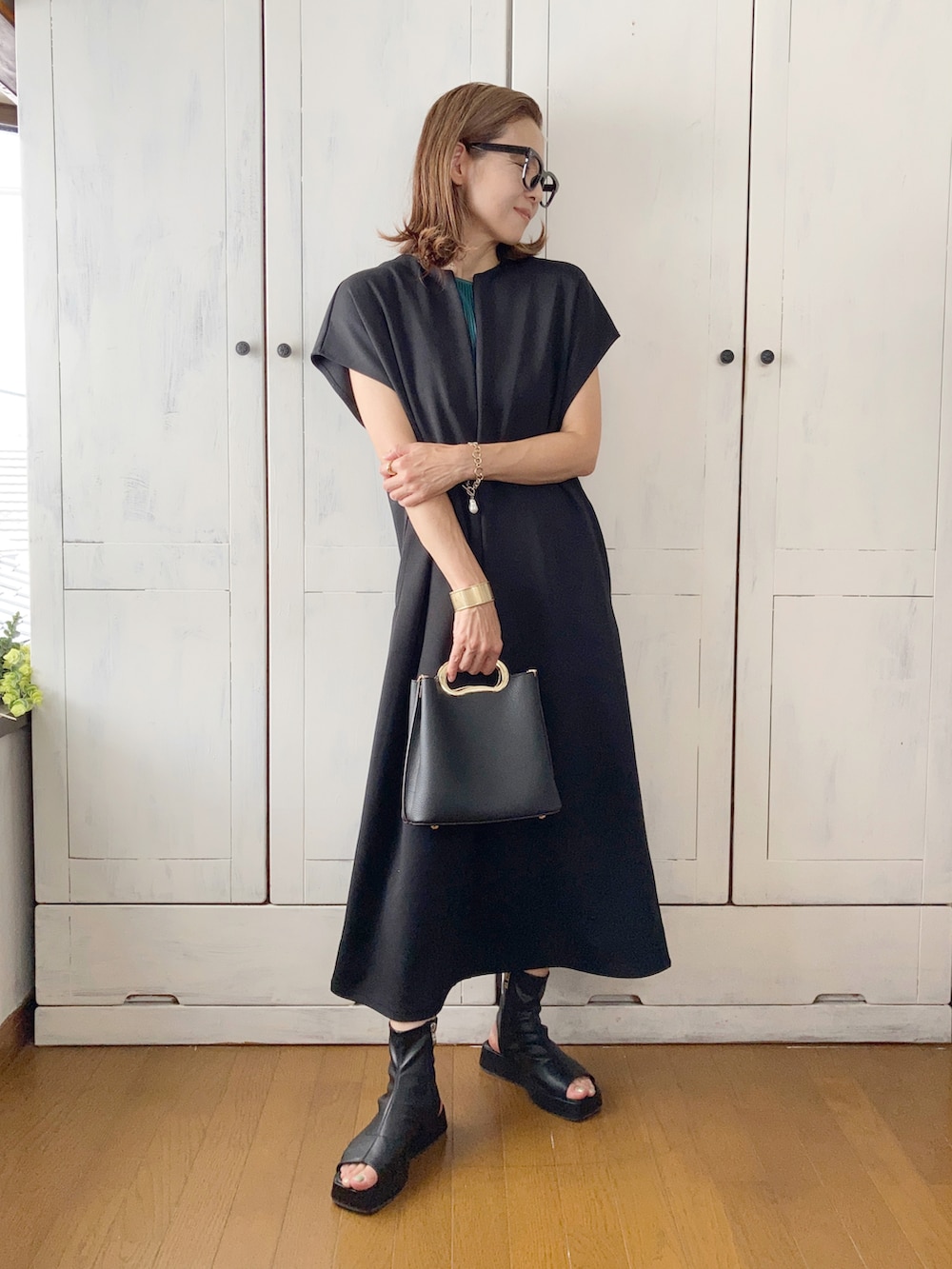 ブラック系のワンピース、グリーン系のパンツ、ブラック系のハンドバッグを着用したレディースの夏コーディネートの2枚目の写真