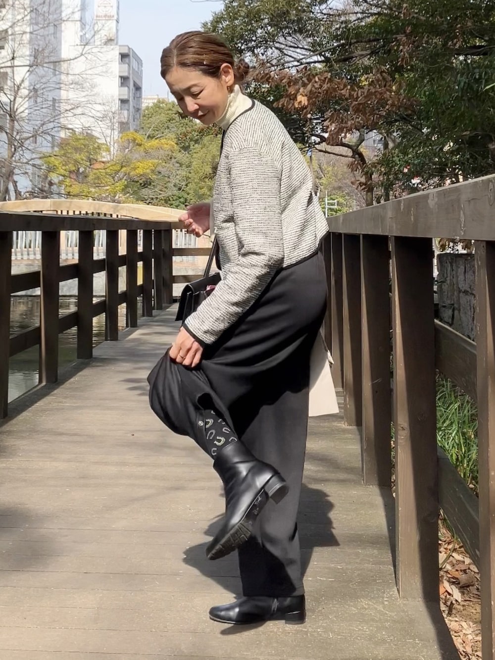 ホワイト系のノーカラージャケット、ブラック系のスウェットパンツ、ブラック系のビジネスバッグを着用したレディースの冬コーディネートの2枚目の写真