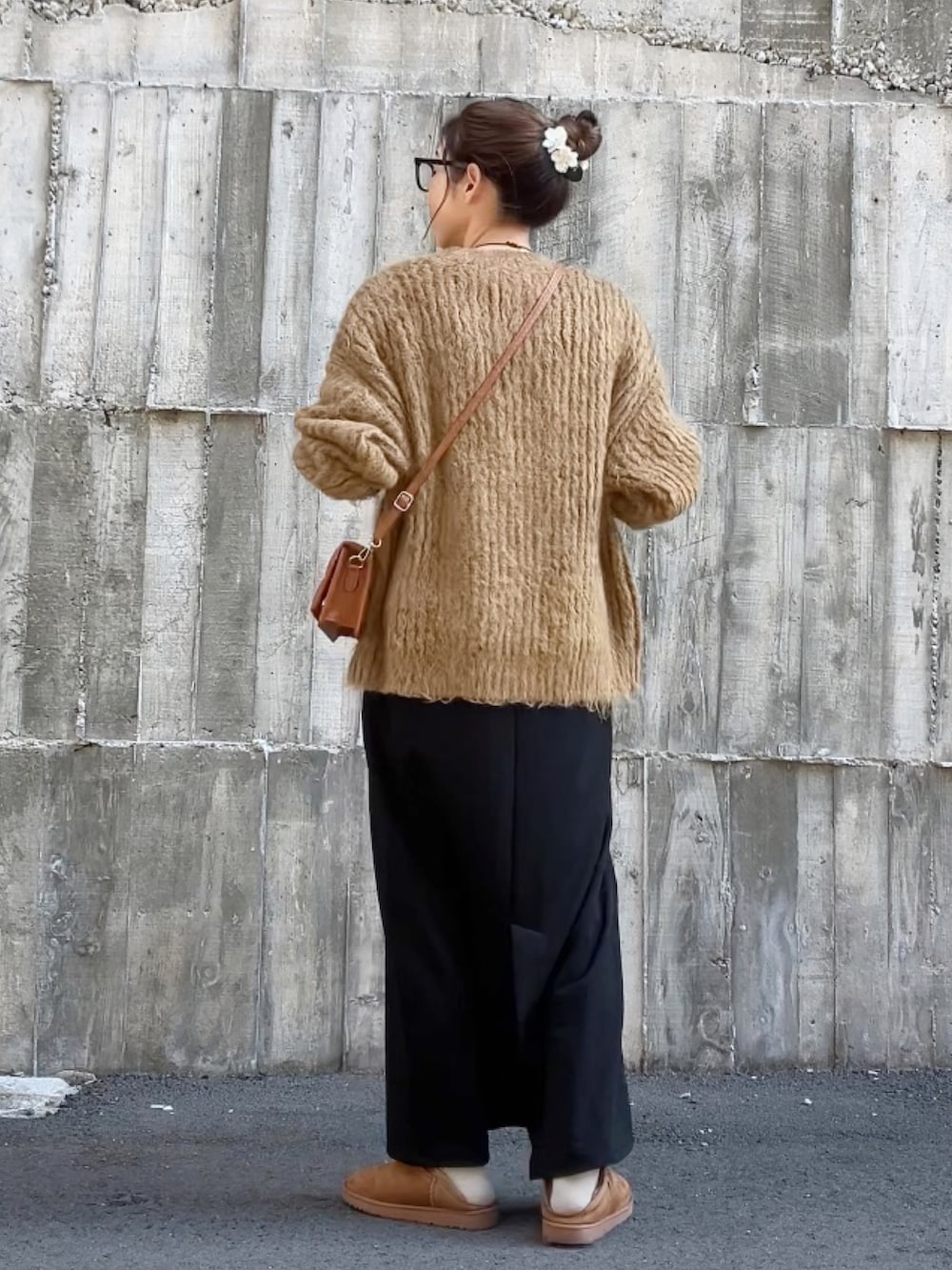 ブラック系のジャンパースカート、ブラウン系のニット/セーター、ブラウン系のクラッチバッグを着用したレディースの冬コーディネートの4枚目の写真