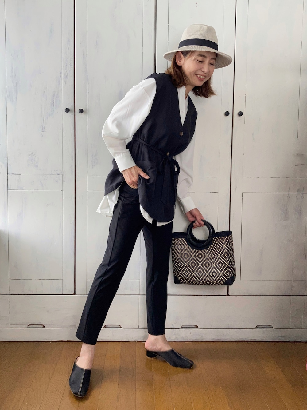 ホワイト系のシャツ/ブラウス、ブラック系のベスト、ブラック系のパンツを着用したレディースの夏コーディネートの2枚目の写真