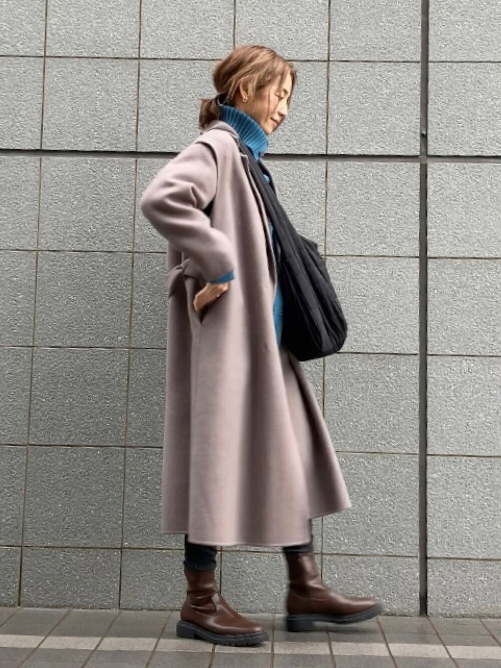 ブラウン系のチェスターコート、ブルー系のニット/セーター、ブラック系のショルダーバッグを着用したレディースの秋コーディネートの2枚目の写真