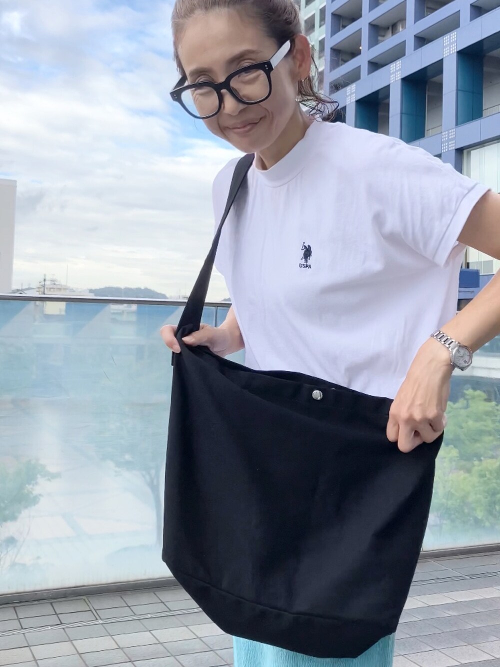 ブラック系のショルダーバッグ、ホワイト系のTシャツ/カットソー、ブルー系のスカートを着用したレディースの夏コーディネートの2枚目の写真