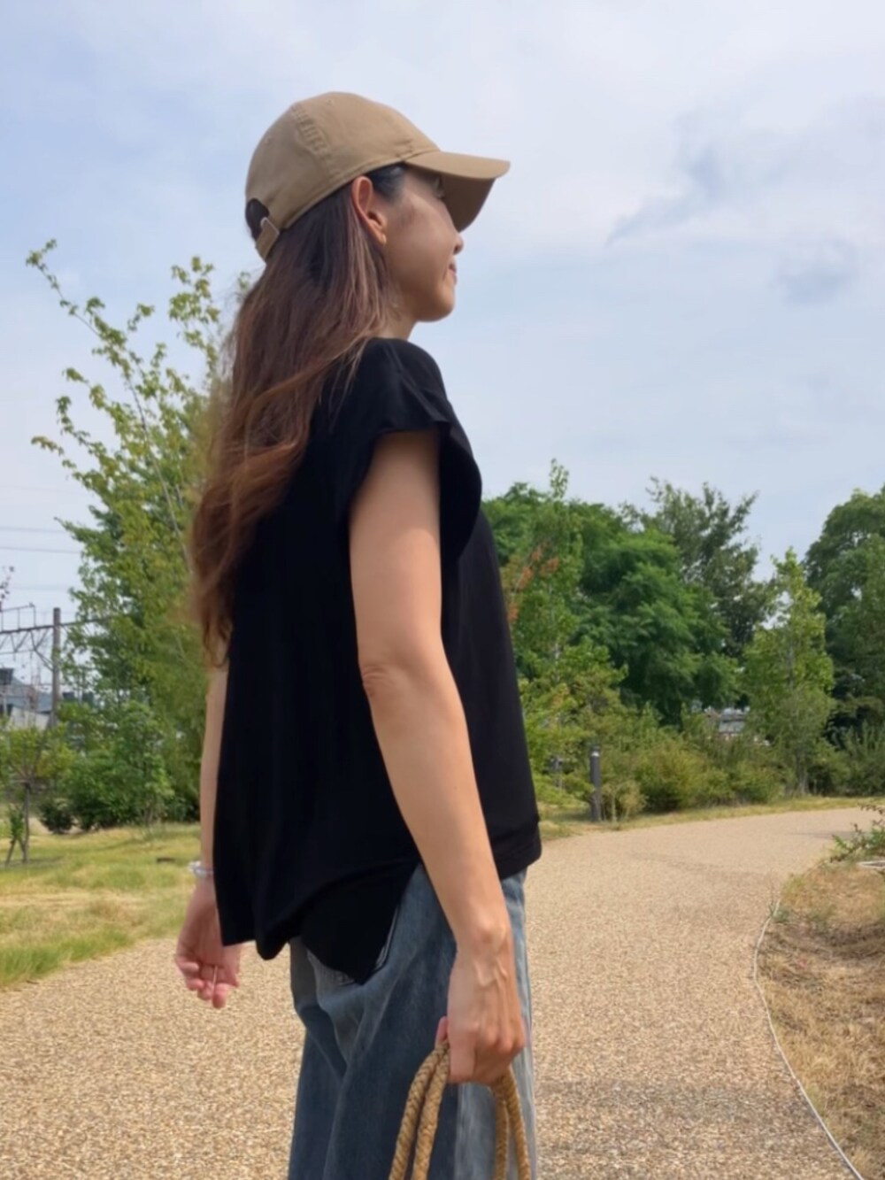 ブラック系のTシャツ/カットソー、ブラウン系のバッグ、ベージュ系のキャップを着用したレディースの夏コーディネートの4枚目の写真