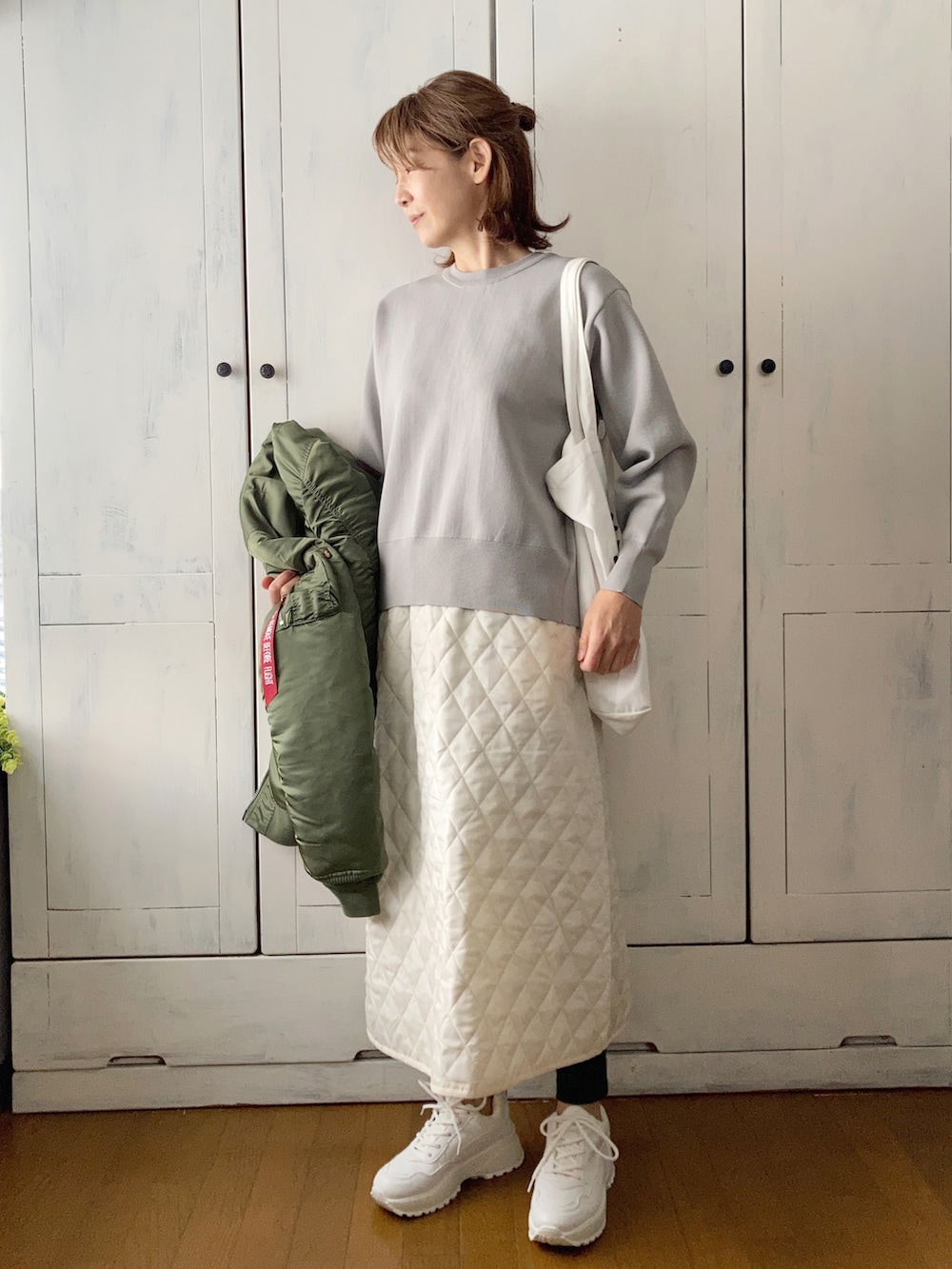 グリーン系のMA-1、グレー系のカーディガン/ボレロ、ホワイト系のスカートを着用したレディースの冬コーディネートの2枚目の写真