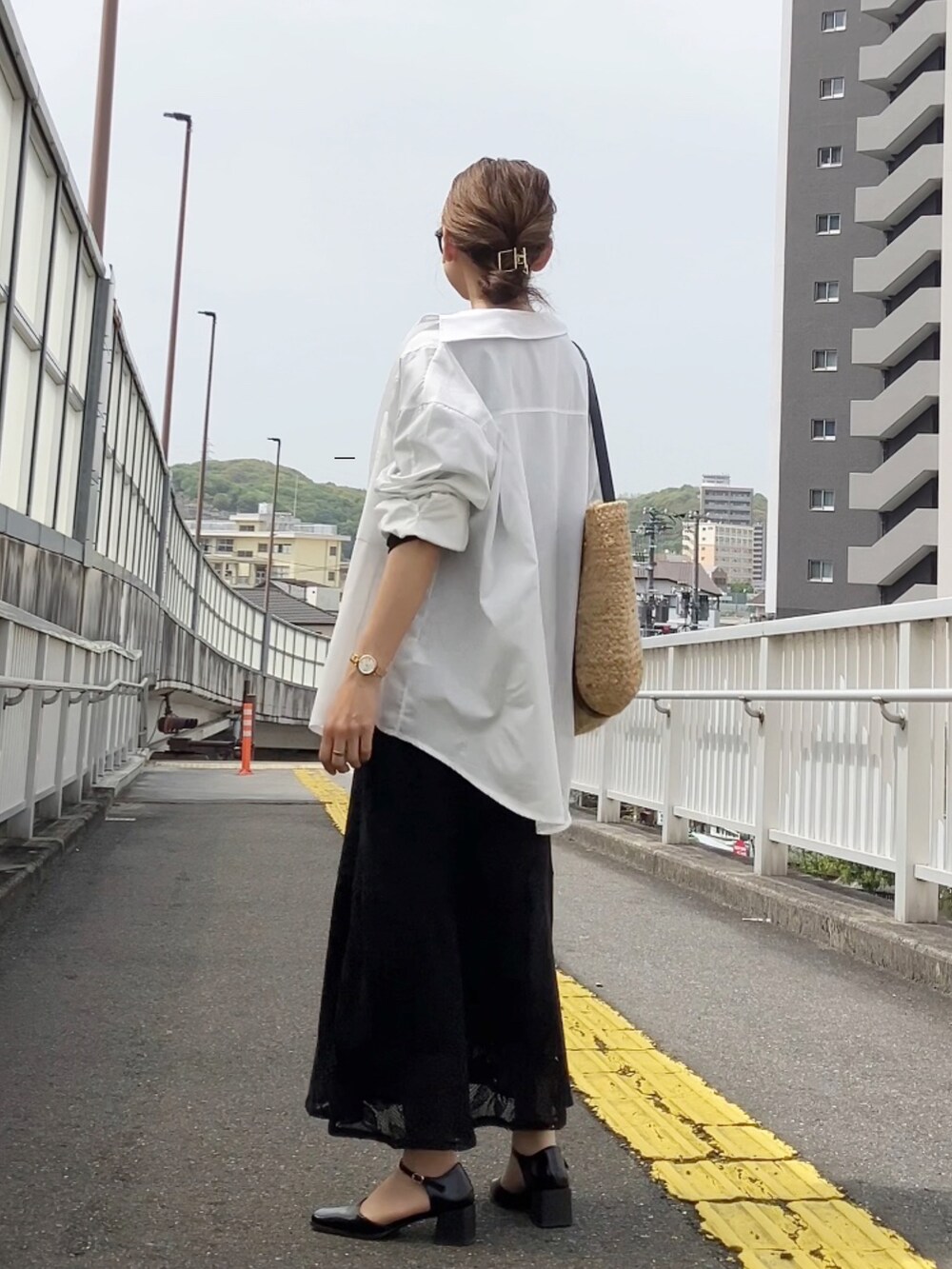 ブラック系のワンピース、ホワイト系のシャツ/ブラウス、ブラック系のパンプスを着用したレディースの春コーディネートの2枚目の写真