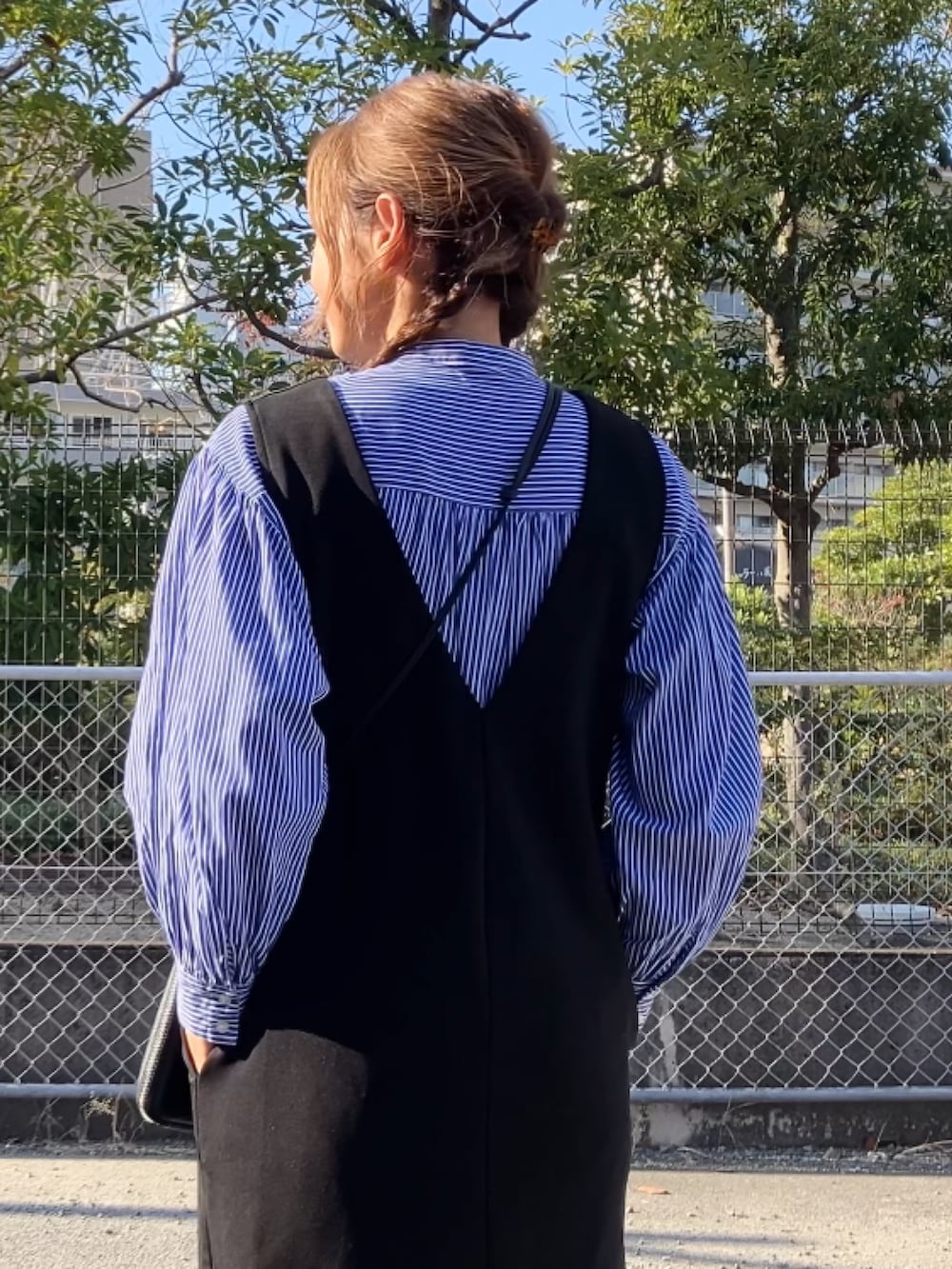 ブラック系のジャンパースカート、ブラック系のバッグ、ホワイト系のスニーカーを着用したレディースの冬コーディネートの3枚目の写真