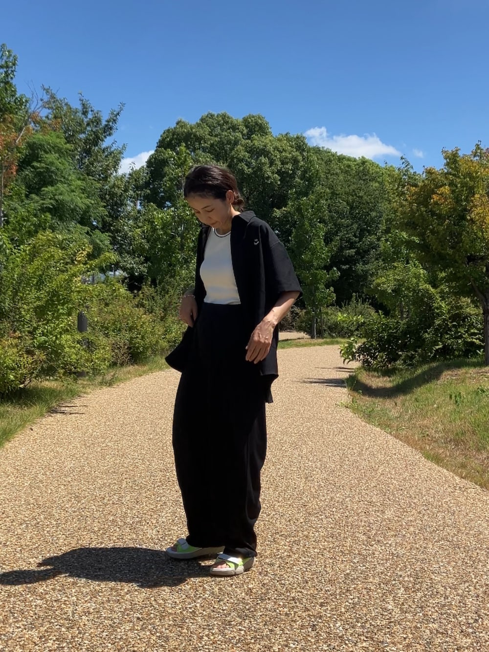 ブラック系のスラックス、イエロー系のサンダル、ベージュ系のキャップを着用したレディースの夏コーディネートの4枚目の写真