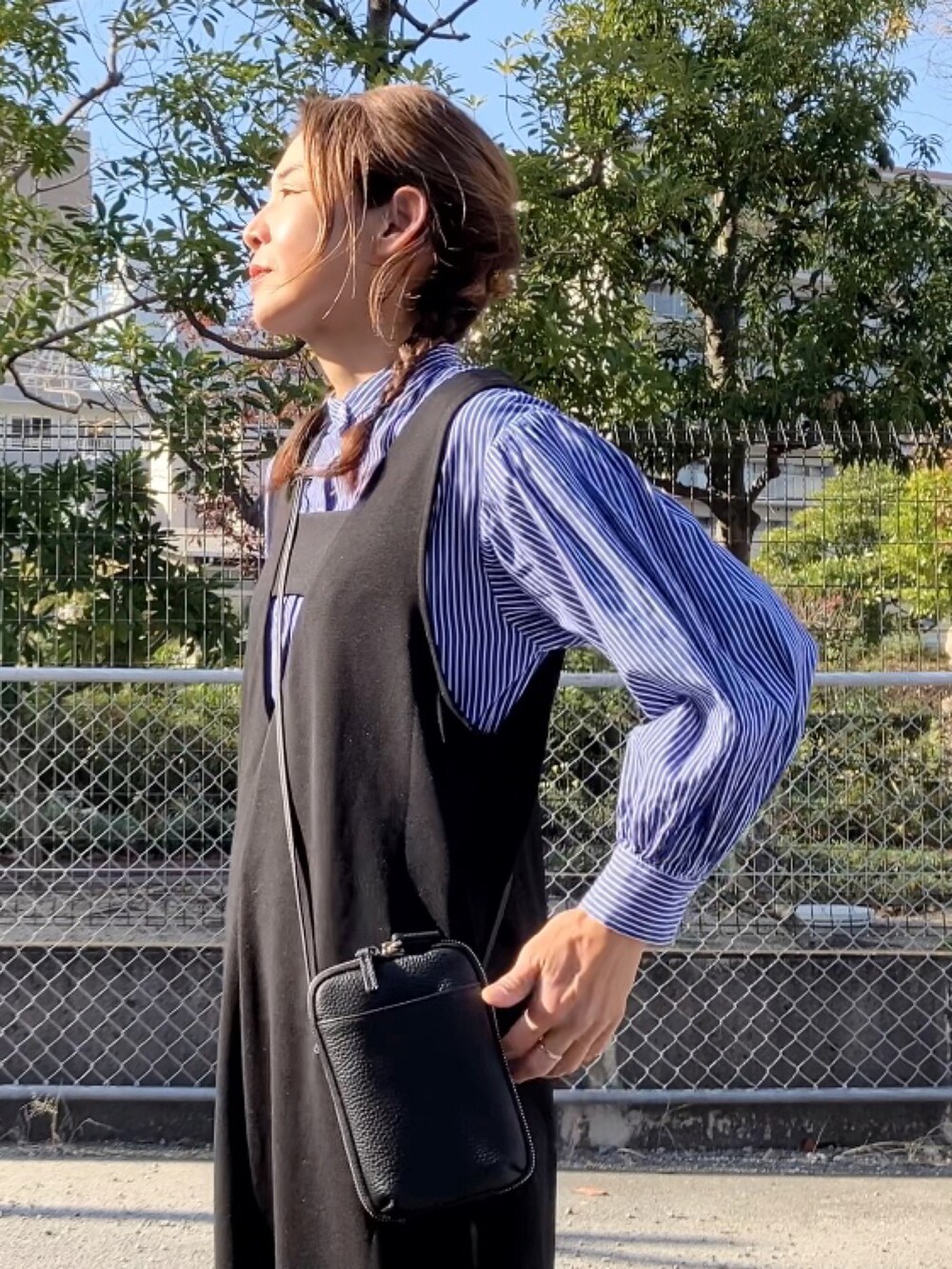 ブラック系のジャンパースカート、ブラック系のバッグ、ホワイト系のスニーカーを着用したレディースの冬コーディネートの2枚目の写真