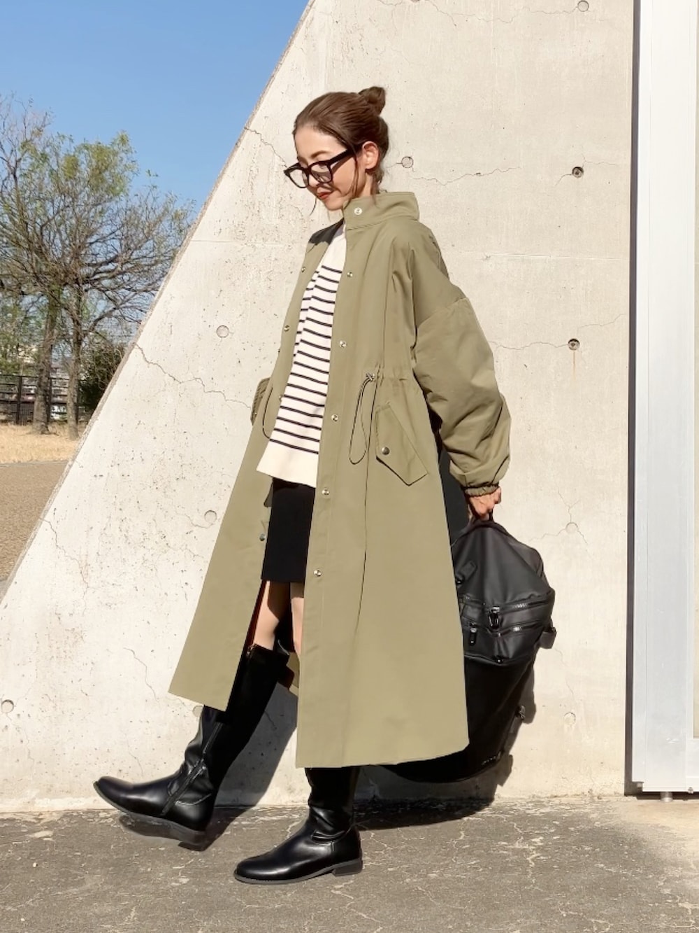 グリーン系のステンカラーコート、ブラック系のバックパック/リュック、ブラウン系のブーツを着用したレディースの秋コーディネートの2枚目の写真