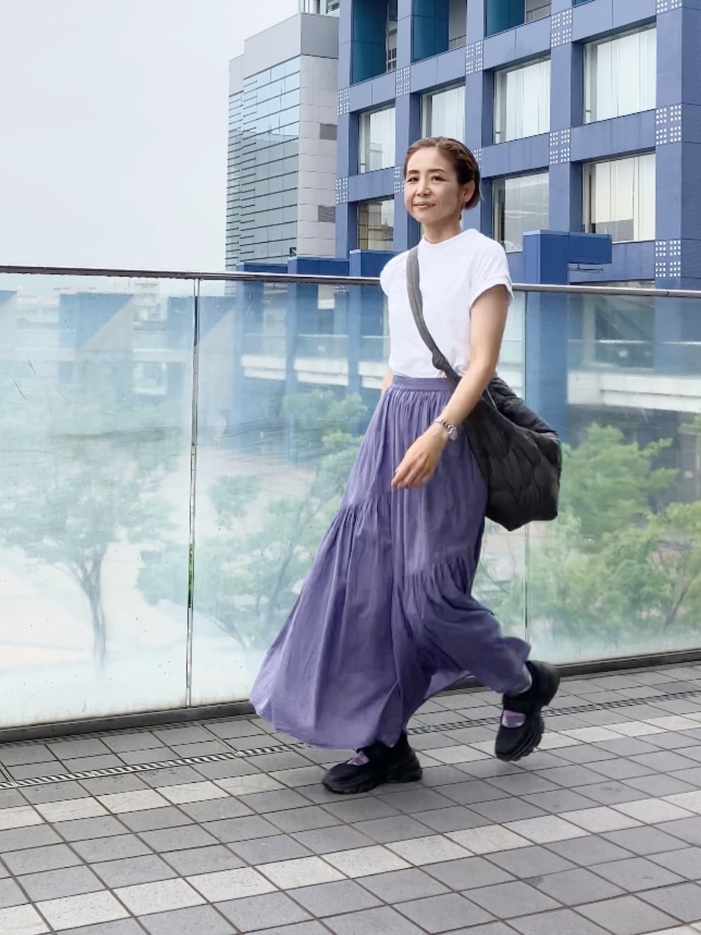 グレー系のスカート、ホワイト系のTシャツ/カットソー、グレー系のショルダーバッグを着用したレディースの夏コーディネートの3枚目の写真