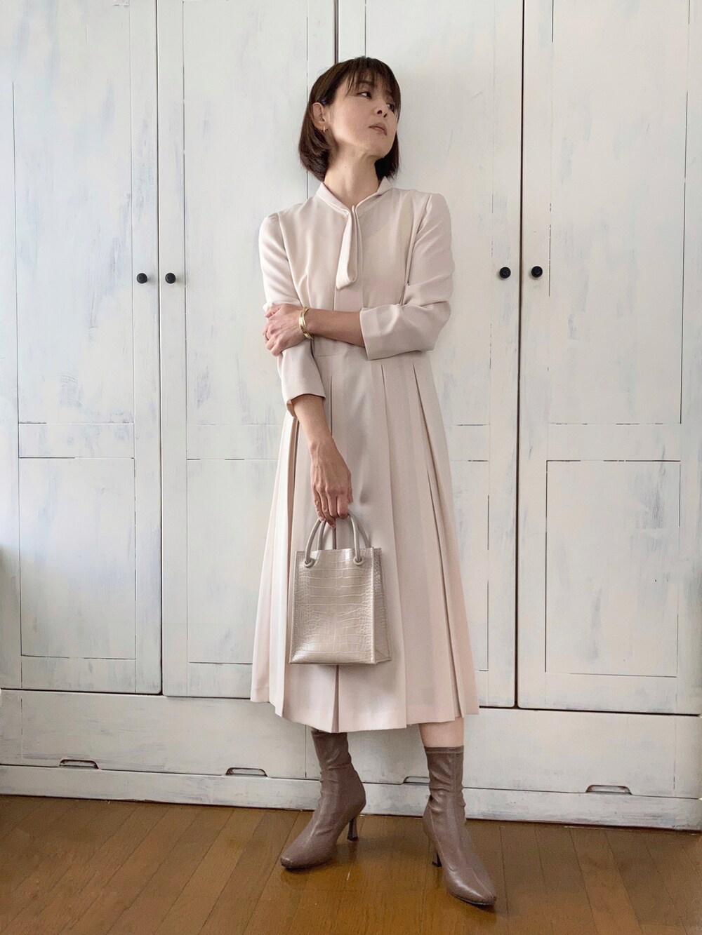 ベージュ系のワンピース、ブルー系のチェスターコート、ベージュ系のショルダーバッグを着用したレディースの冬コーディネートの3枚目の写真