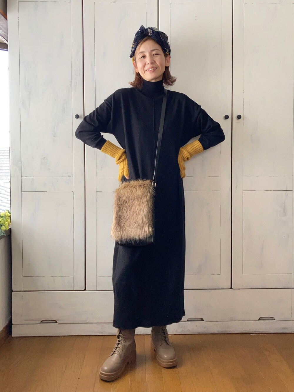 ブラック系のワンピース、ブラウン系のショルダーバッグ、ブラウン系のブーツを着用したレディースの秋コーディネートの4枚目の写真