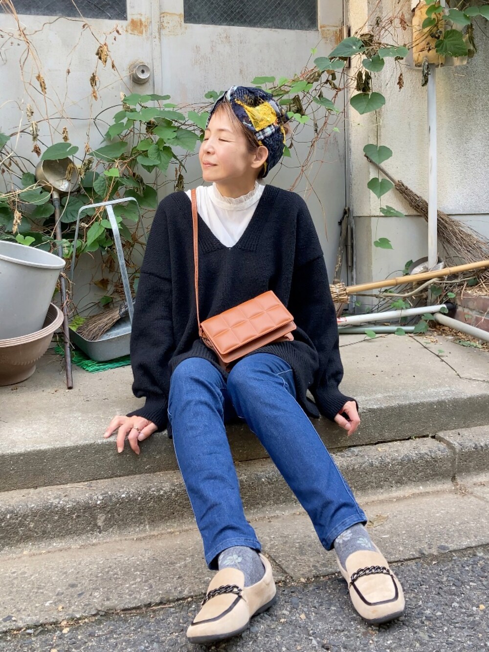 ブラック系のニット/セーター、ブルー系のデニムパンツ、ベージュ系のシューズを着用したレディースの秋コーディネートの2枚目の写真