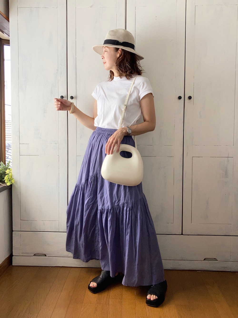 グレー系のスカート、ホワイト系のTシャツ/カットソー、ホワイト系のバッグを着用したレディースの夏コーディネートの2枚目の写真