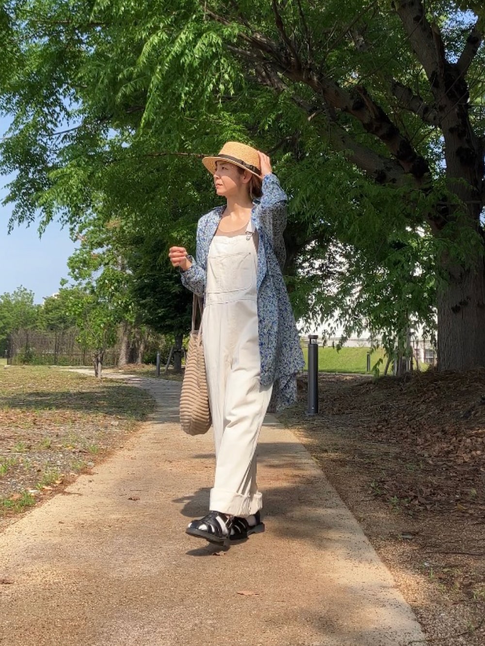 ブルー系のシャツワンピース、ホワイト系のサロペット/オーバーオール、ベージュ系のバッグを着用したレディースの春コーディネートの4枚目の写真