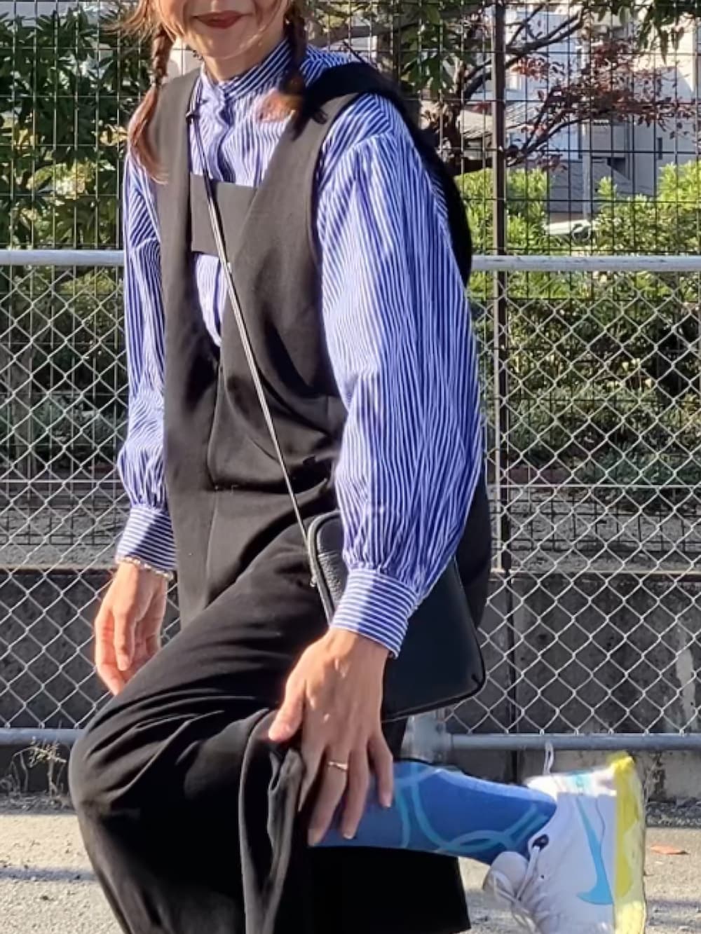 ブラック系のジャンパースカート、ブラック系のバッグ、ホワイト系のスニーカーを着用したレディースの冬コーディネートの4枚目の写真