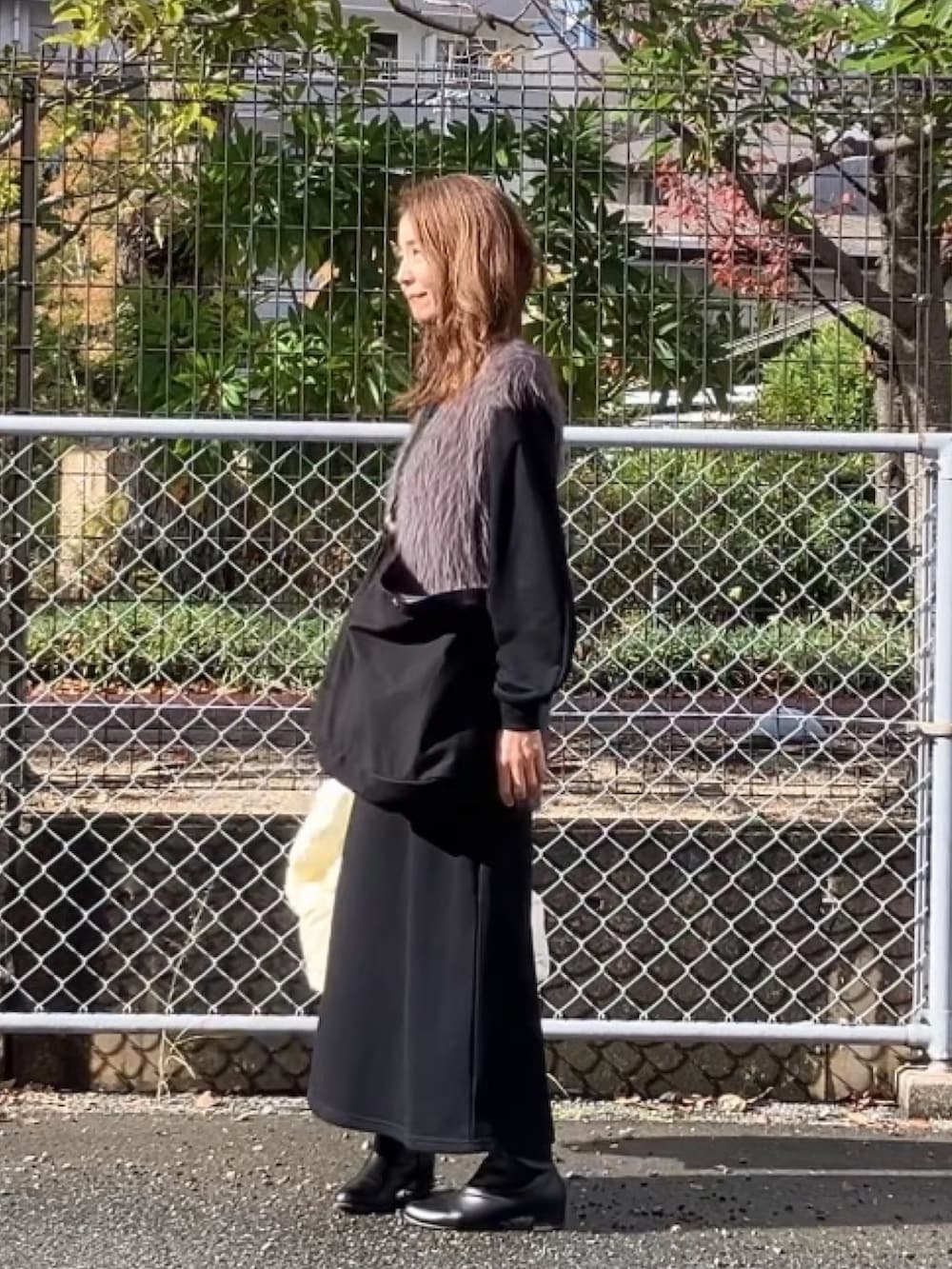 ホワイト系のダウンベスト、ブラック系のワンピース、グレー系のニット/セーターを着用したレディースの冬コーディネートの2枚目の写真