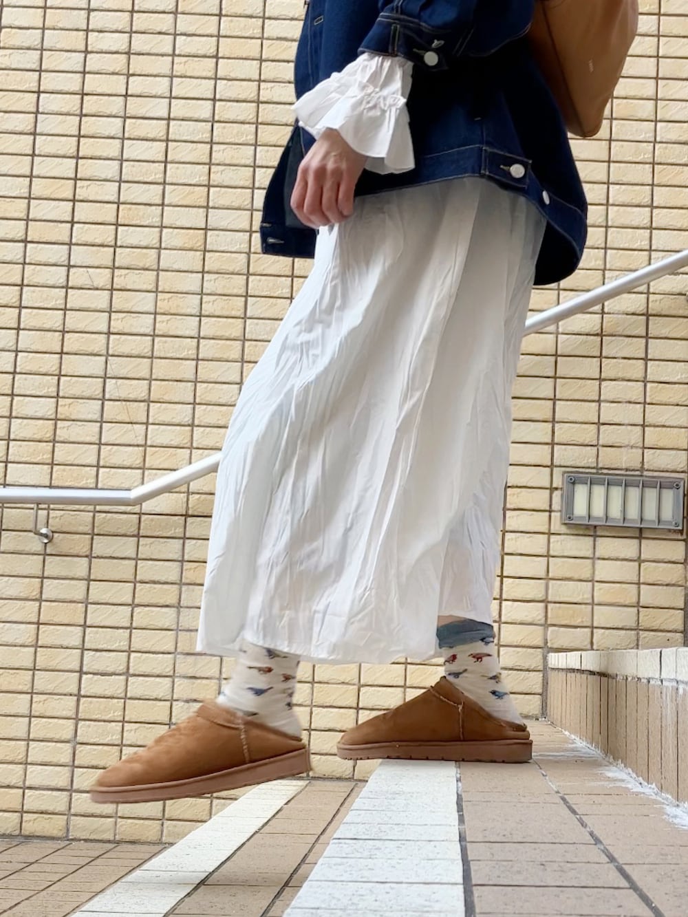 ベージュ系のベスト、ブルー系のデニムジャケット、ホワイト系のワンピースを着用したレディースの春コーディネートの2枚目の写真