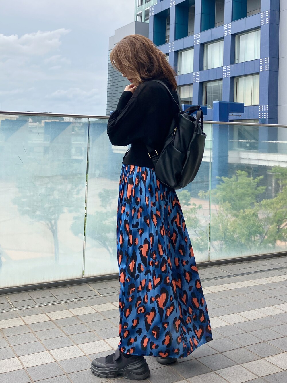 ブルー系のスカート、ブラック系のカーディガン/ボレロ、ブラック系のバックパック/リュックを着用したレディースの秋コーディネートの3枚目の写真