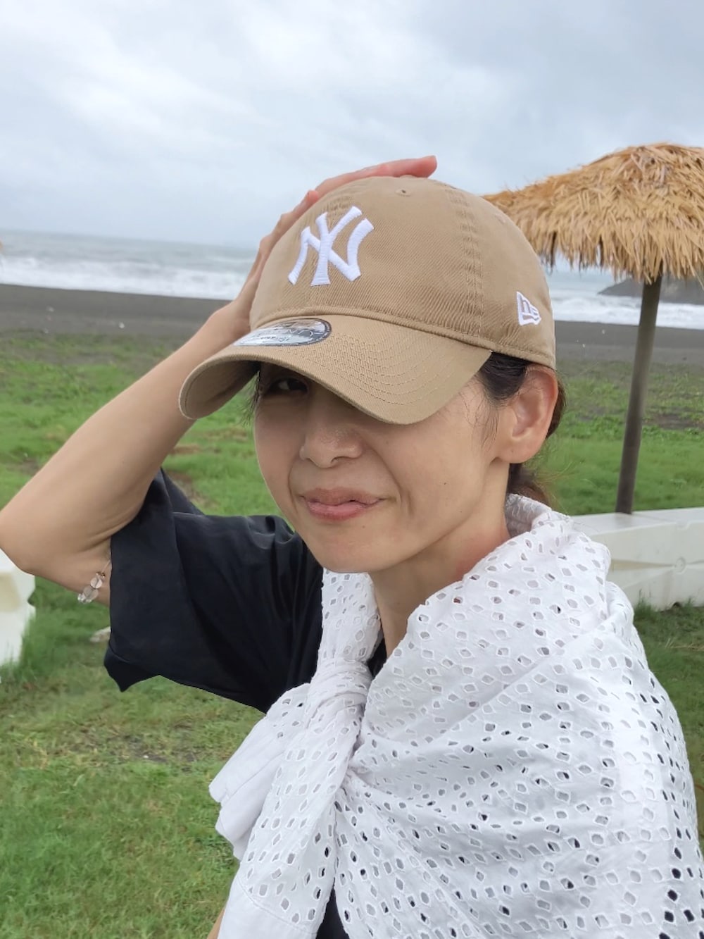 ブラック系のトップス、ベージュ系のショルダーバッグ、ブラック系のパンツを着用したレディースの夏コーディネートの2枚目の写真