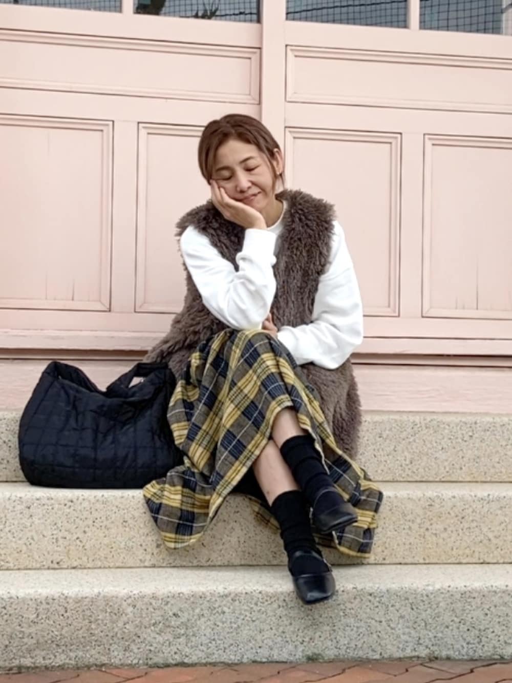 ホワイト系のスウェット、グレー系のベスト、イエロー系のスカートを着用したレディースの秋コーディネートの2枚目の写真