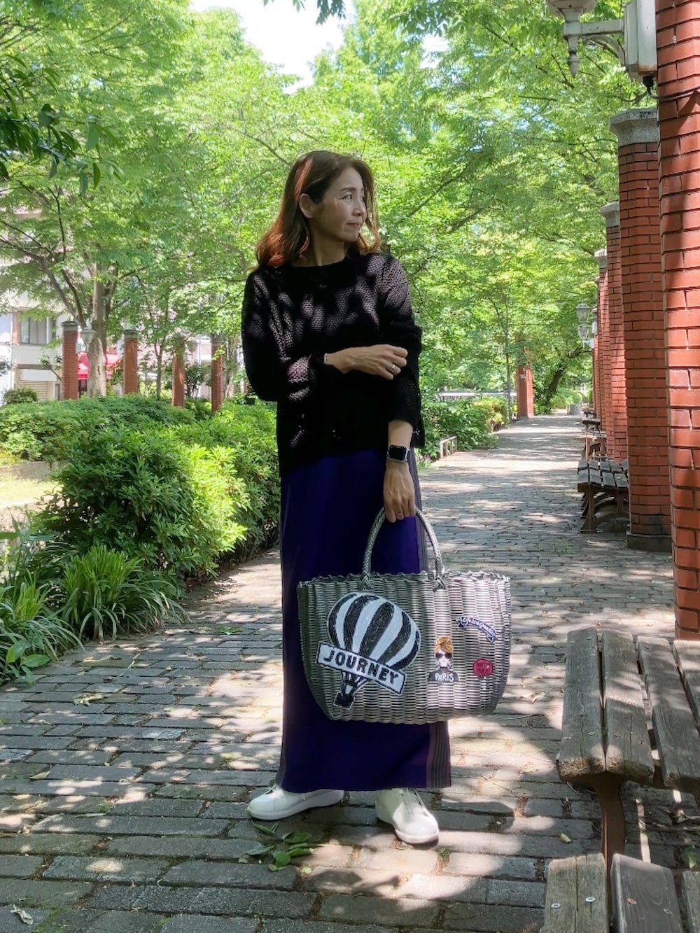 パープル系のスカート、グレー系のバッグ、ホワイト系のスニーカーを着用したレディースの春コーディネートの3枚目の写真