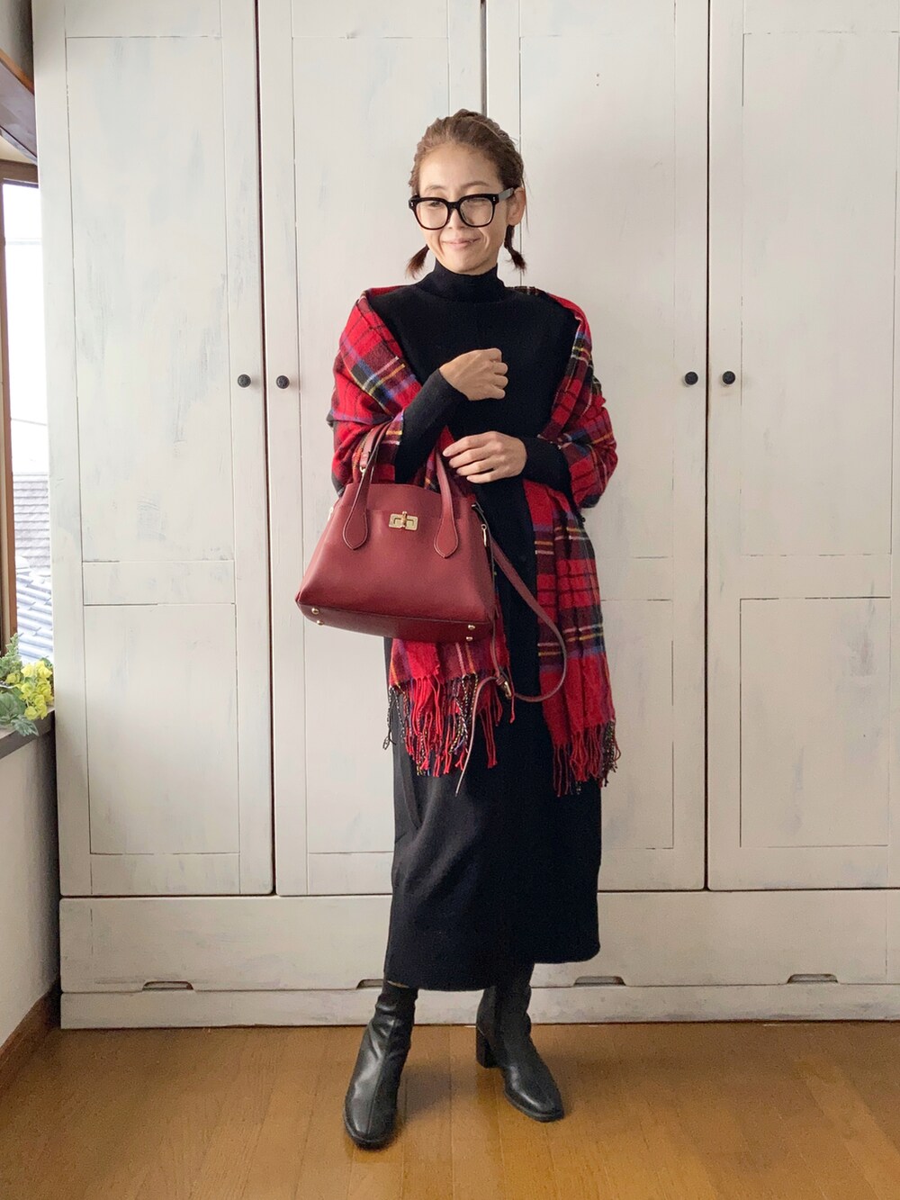 ブラック系のワンピース、レッド系のハンドバッグ、ブラック系のブーツを着用したレディースの秋コーディネートの3枚目の写真