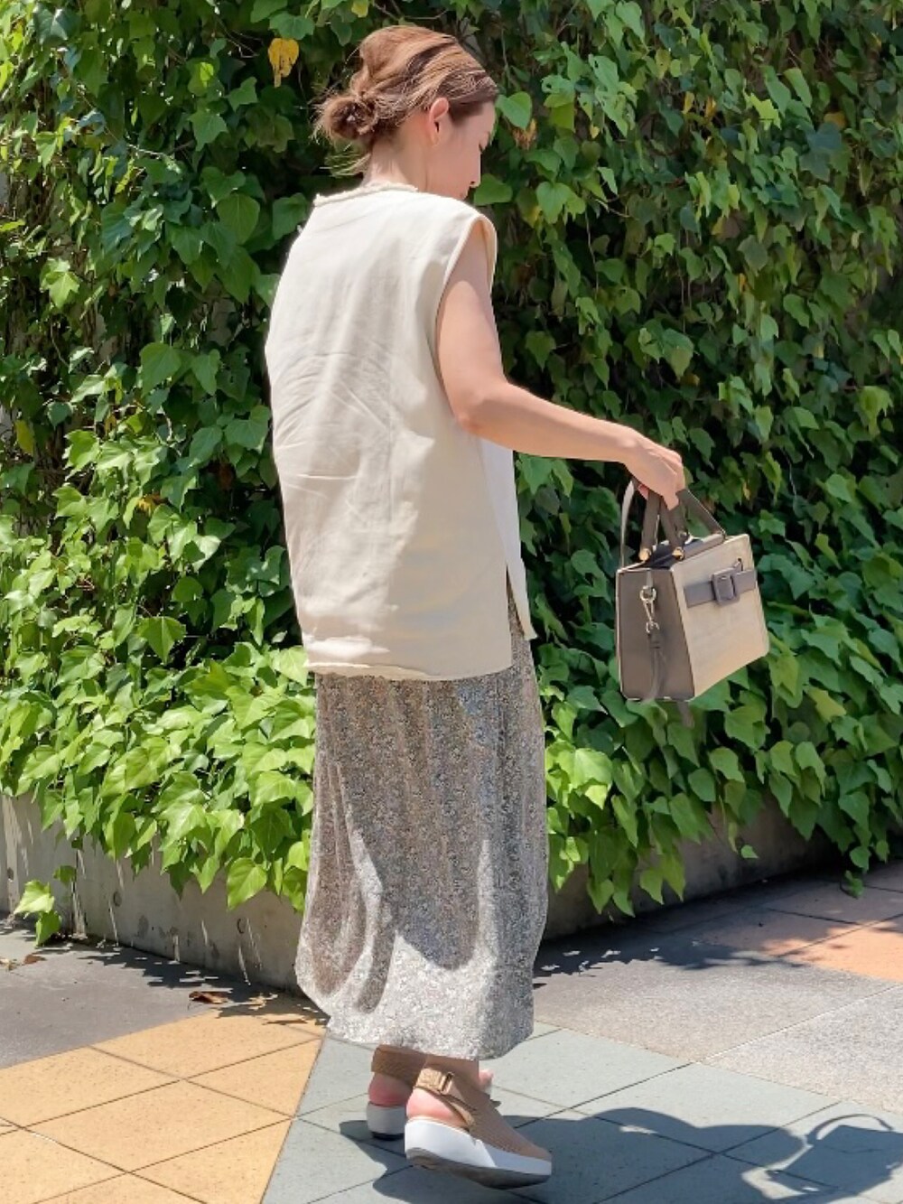 ベージュ系のベスト、グリーン系のワンピース、グレー系のハンドバッグを着用したレディースの夏コーディネートの3枚目の写真