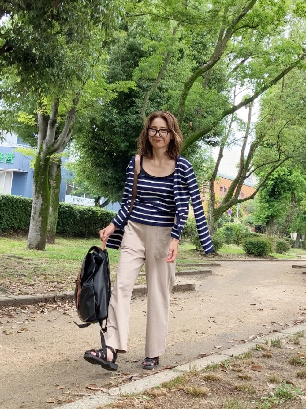 ブルー系のアンサンブル、ベージュ系のパンツ、ブラック系のサンダルを着用したレディースの夏コーディネートの2枚目の写真