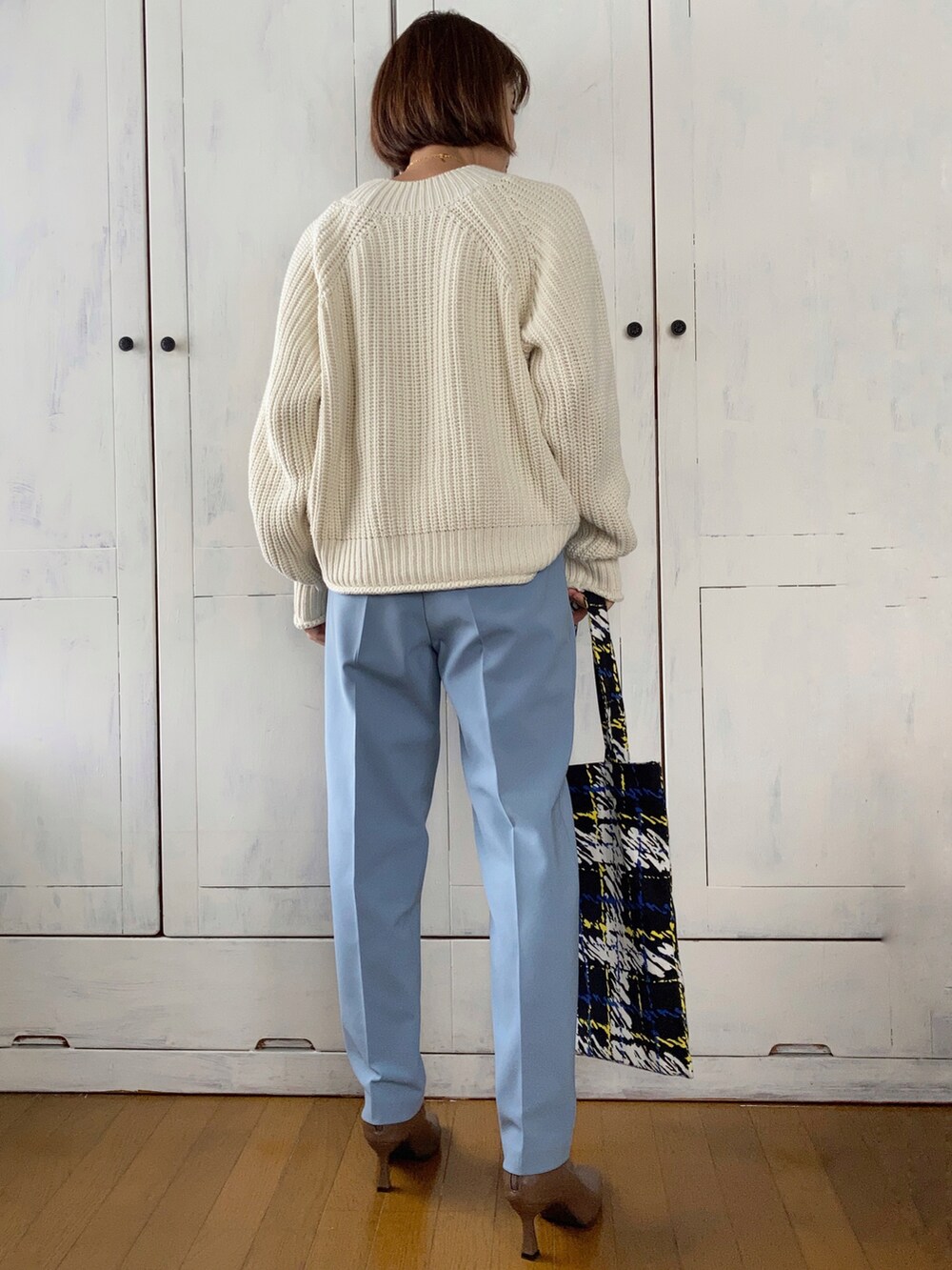 ブラック系のノーカラーコート、ホワイト系のニット/セーター、ブルー系のその他パンツを着用したレディースの秋コーディネートの3枚目の写真