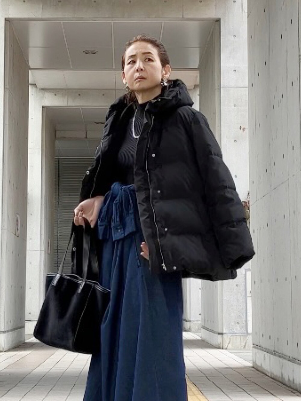 ブラック系のダウンジャケット/コート、ブラック系のトートバッグ、ブラック系のニット/セーターを着用したレディースの冬コーディネートの3枚目の写真