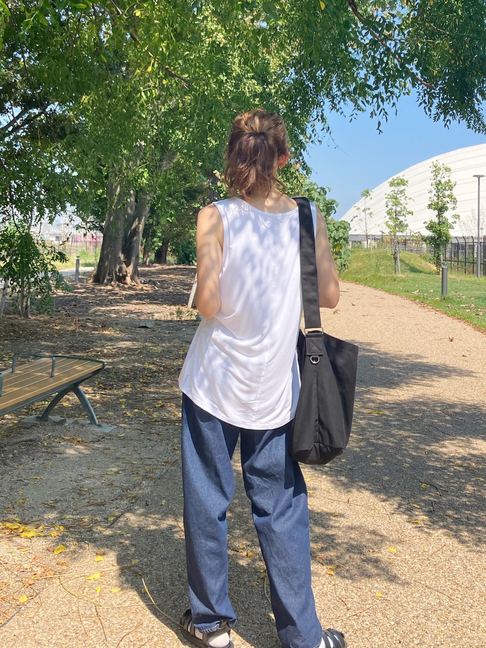 ホワイト系のタンクトップ、ブルー系のデニムパンツ、ブラック系のショルダーバッグを着用したレディースの夏コーディネートの3枚目の写真