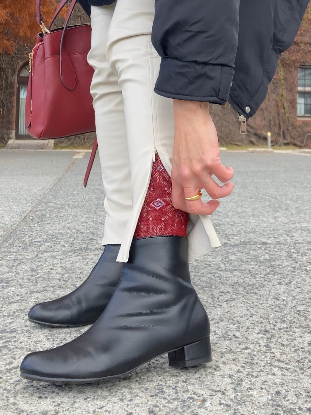 ブラック系のブルゾン、ブラック系のニット/セーター、ホワイト系のパンツを着用したレディースの冬コーディネートの5枚目の写真