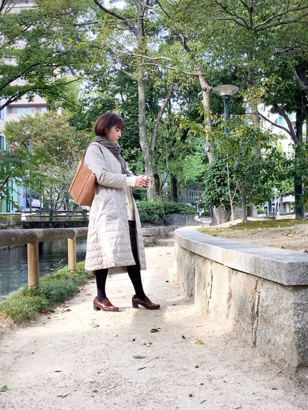 ベージュ系のダウンジャケット/コート、ホワイト系のカーディガン/ボレロ、ブラウン系のスカートを着用したレディースの秋コーディネートの3枚目の写真