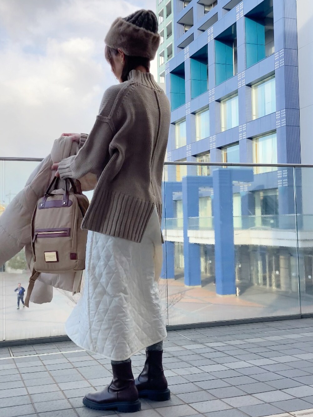 ホワイト系のダウンジャケット/コート、ベージュ系のニット/セーター、ホワイト系のスカートを着用したレディースの冬コーディネートの3枚目の写真