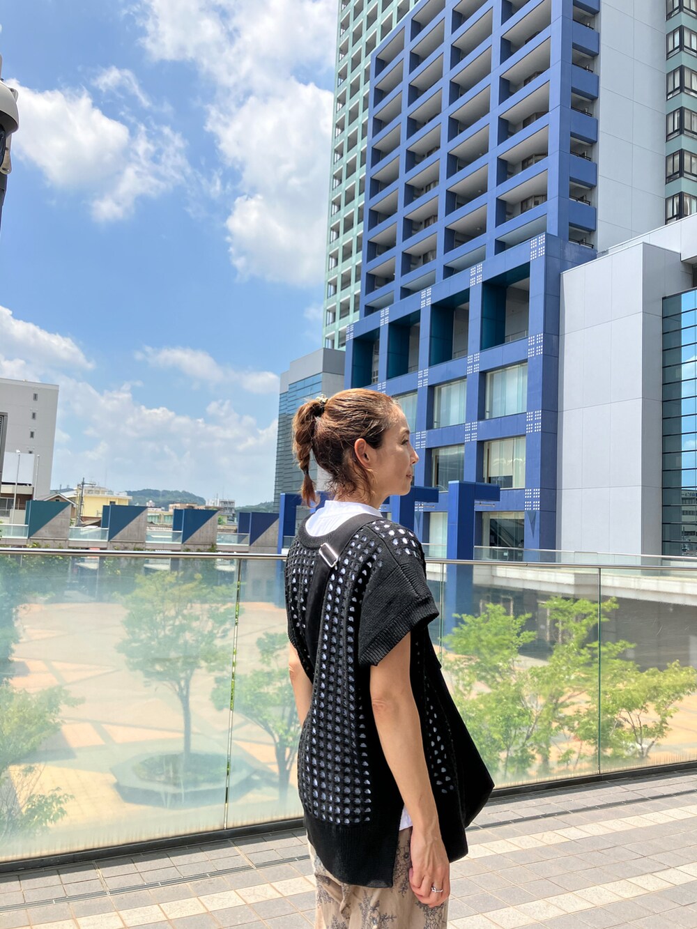 ブラック系のベスト、ホワイト系のTシャツ/カットソー、ブラック系のショルダーバッグを着用したレディースの夏コーディネートの2枚目の写真