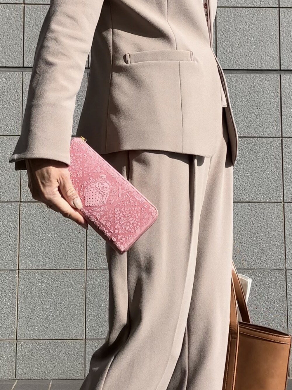 ベージュ系のスーツセット、ベージュ系のパンプス、ブラウン系のバッグを着用したレディースの冬コーディネートの2枚目の写真